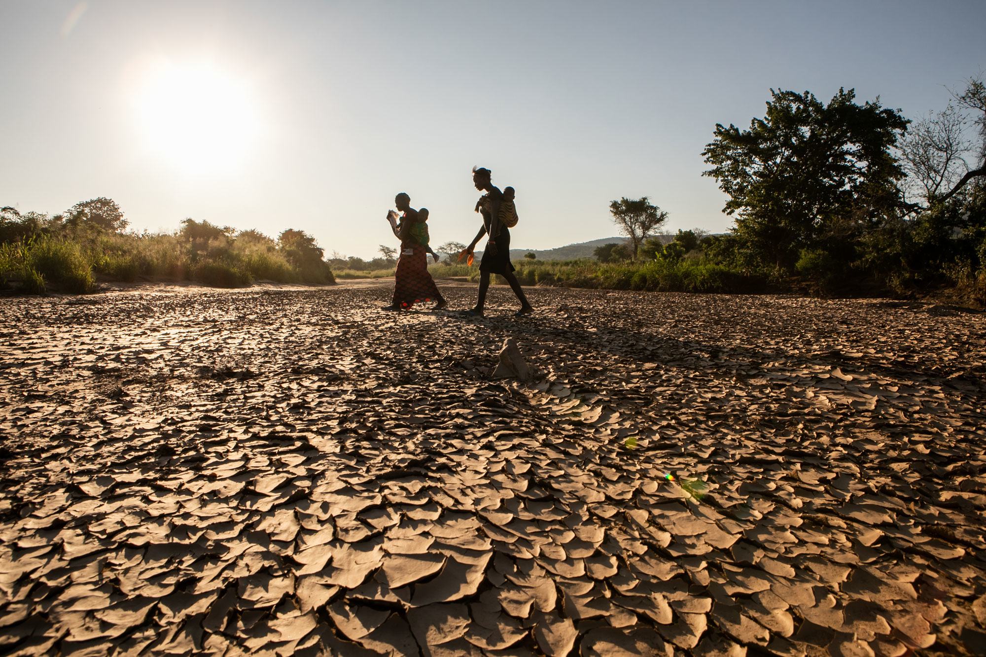 امرأتان تمشيان إلى منزلها عبر مجرى نهر جاف في وادي غويمبي، زامبيا.