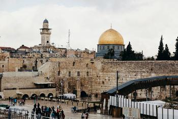 منظر قبة الصخرة والجدار الغربي في القدس، إسرائيل، مع السياح في الساحة الحجرية أدناه في يوم غائم.