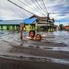 أطفال يشقون طريقهم في مياه الفيضانات في بالانجكا رايا في وسط كاليمانتان بإندونيسيا.