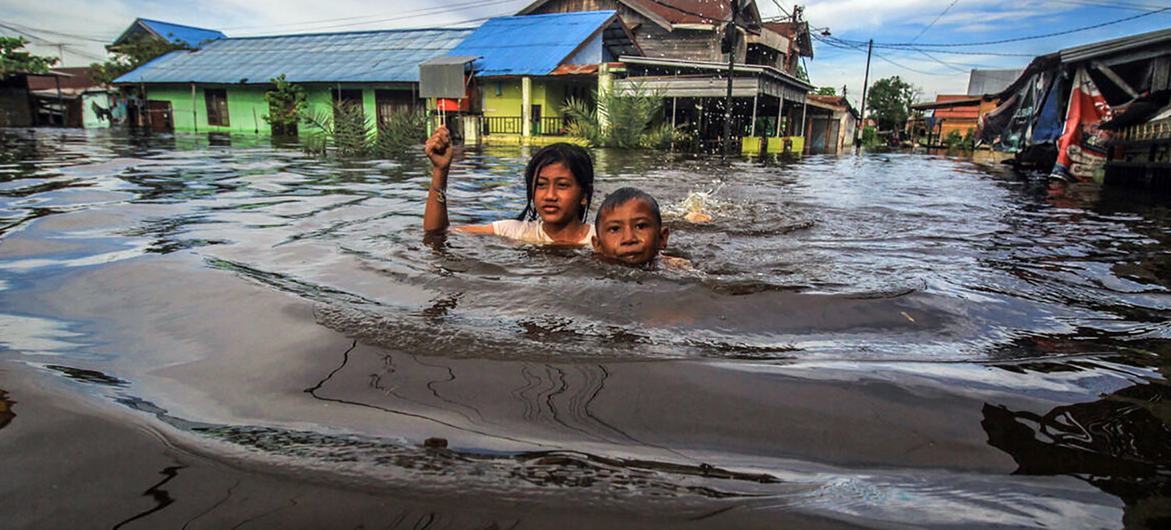 Unos niños caminan entre las aguas de las inundaciones en Palangka Raya, en Kalimantan Central (Indonesia). 