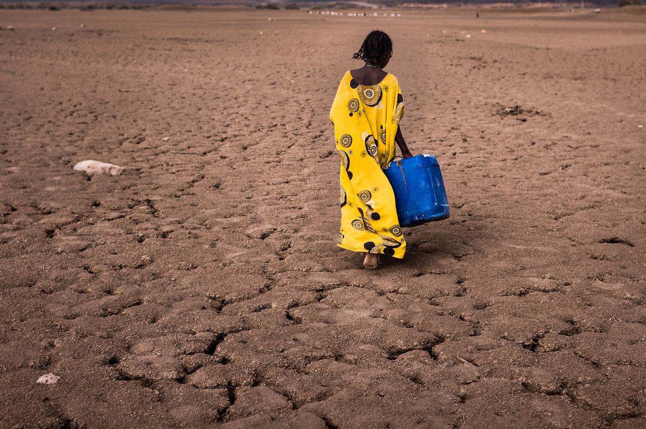 在埃塞俄比亚的阿法尔地区，一名女孩拿着一个打水的容器行走。