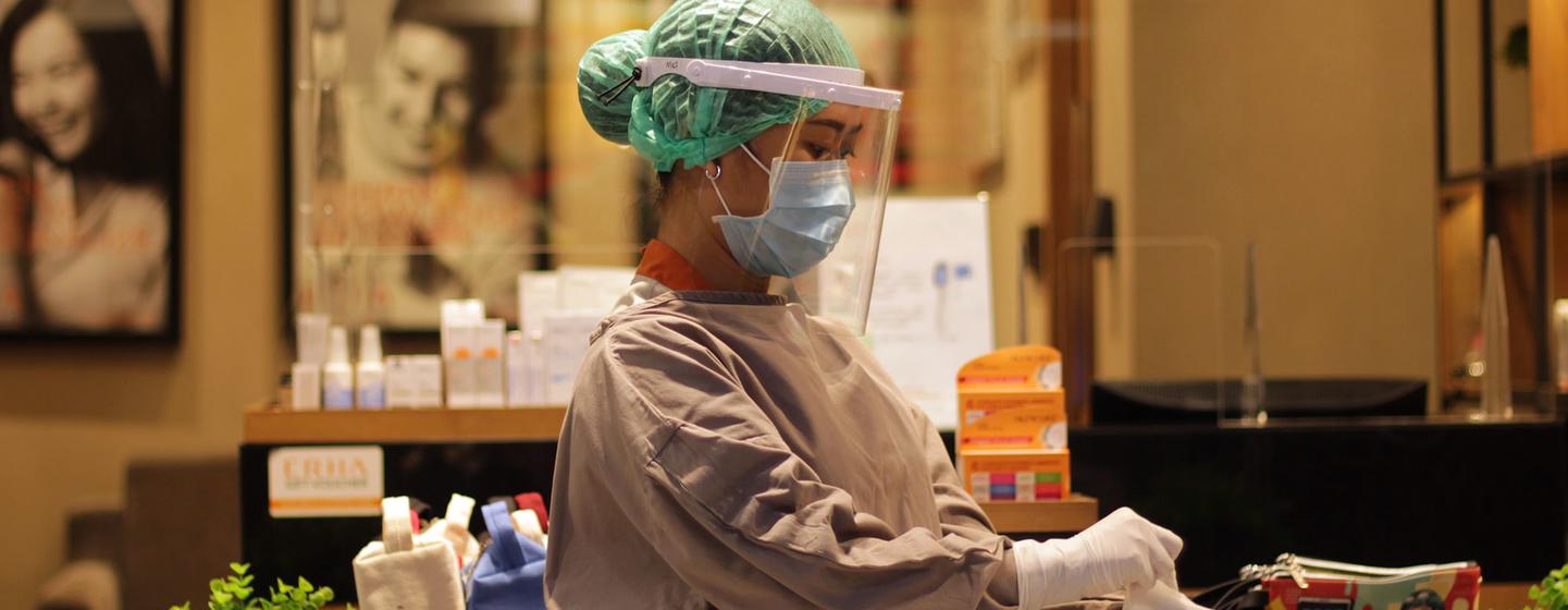 Un agent de santé en Indonésie se protège contre les infections alors qu'elle se prépare à traiter un patient.