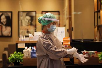 इंडोनेशिया में एक स्वास्थ्यकर्मी, मरीज़ के उपचार के लिए जाने से पहले संक्रमण से बचाव के उपाय को अपना रही है.