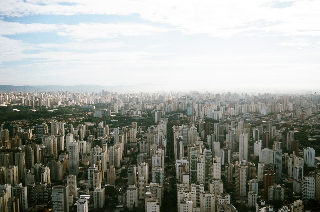 Una vista aérea del denso horizonte urbano de São Paulo, Brasil, que muestra numerosos edificios de gran altura bajo un cielo parcialmente nublado.