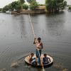 在巴基斯坦信德省，男孩们用一个大平底锅作为临时筏子趟过洪水。