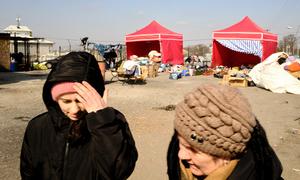 Ukrainian women walk in front of tents set up in Medyka, Poland, to assist refugees fleeing conflict.