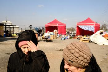 Ukrainian women walk in front of tents set up in Medyka, Poland, to assist refugees fleeing conflict.