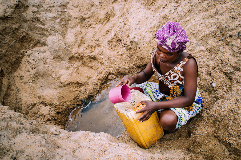 Женщина собирает воду в пересохшем русле реки во время засухи на Мадагаскаре.