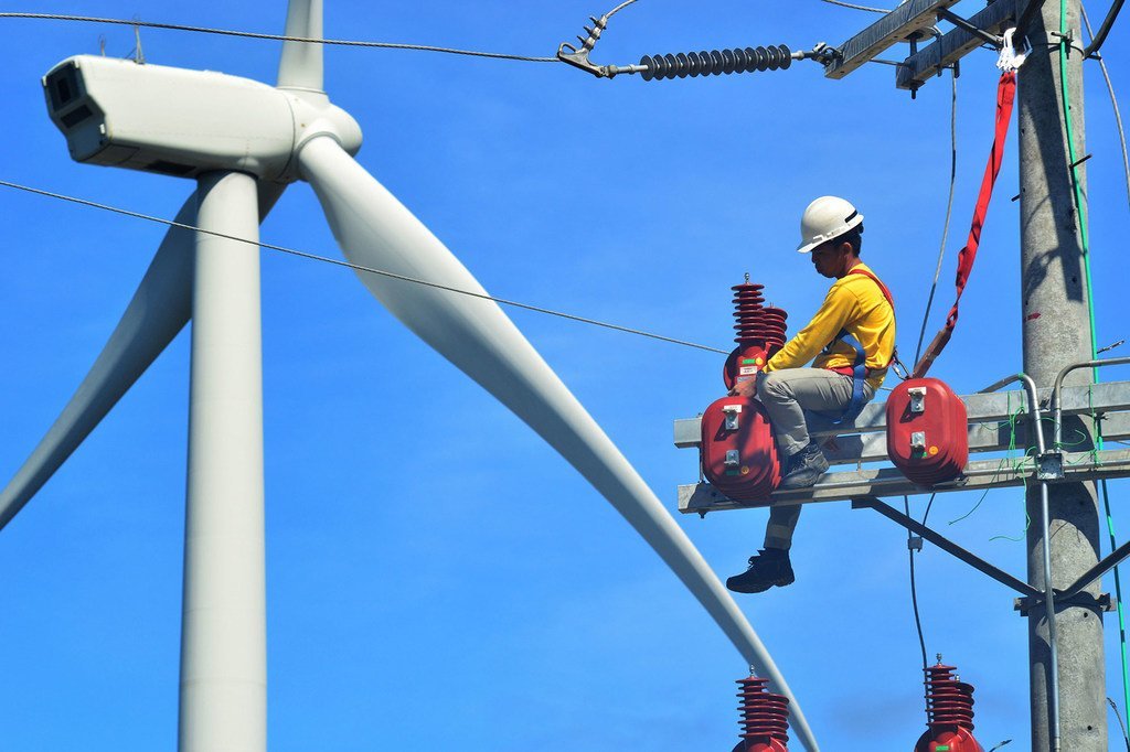 Un technicien travaille sur une éolienne aux Philippines.