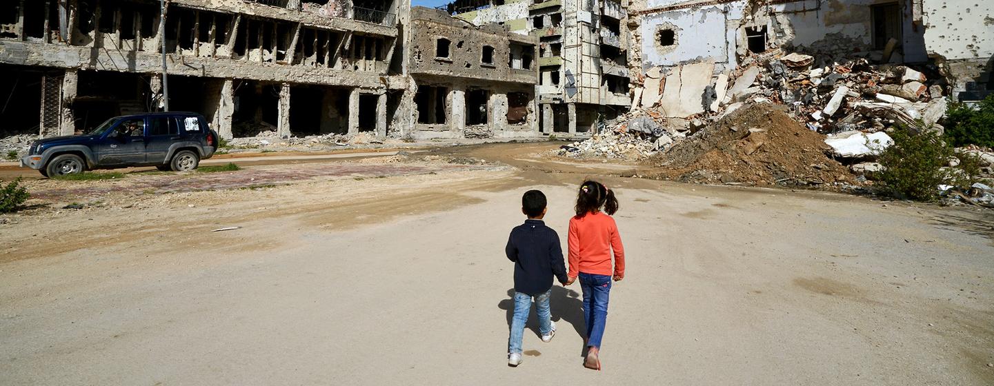 Crianças passam por edifícios danificados em Benghazi, na Líbia.