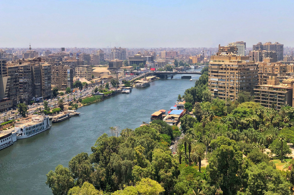 Vista panorámica del río Nilo en El Cairo, Egipto, que muestra el distrito de Agouza a la izquierda y Zamalek a la derecha, con un paisaje urbano y un parque verde en primer plano.