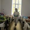 Um profissional de saúde com equipamento de proteção individual caminha por uma ala hospitalar na Ucrânia repleta de pacientes com COVID-19.