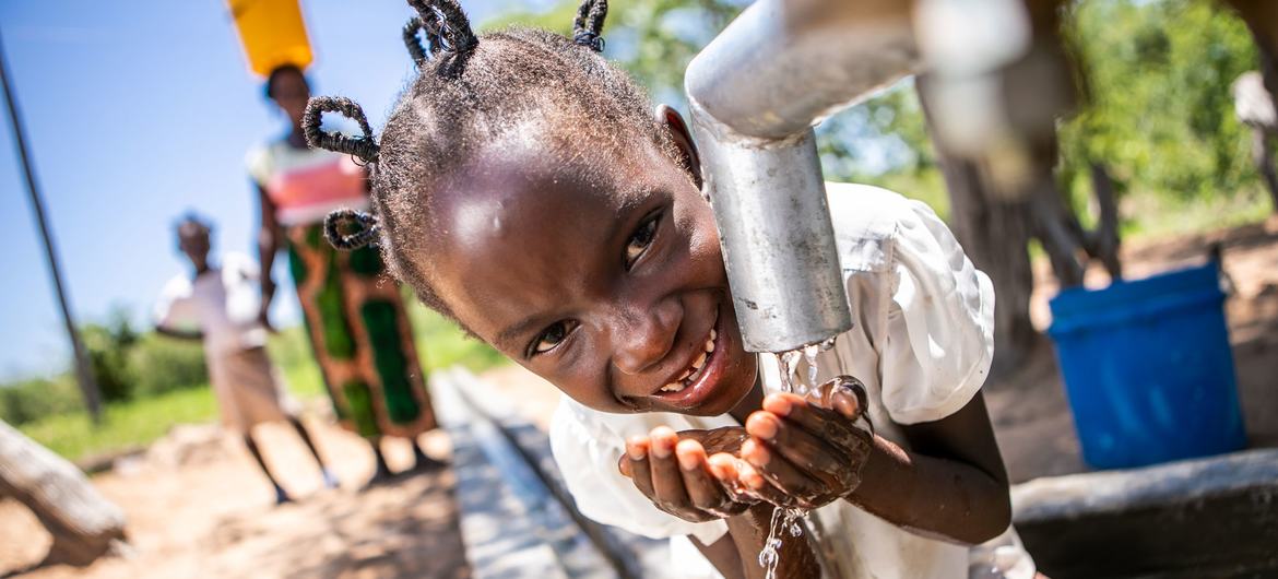 Uma jovem no Zimbábue bebe água limpa e segura de um poço reabilitado com o apoio da ONU.