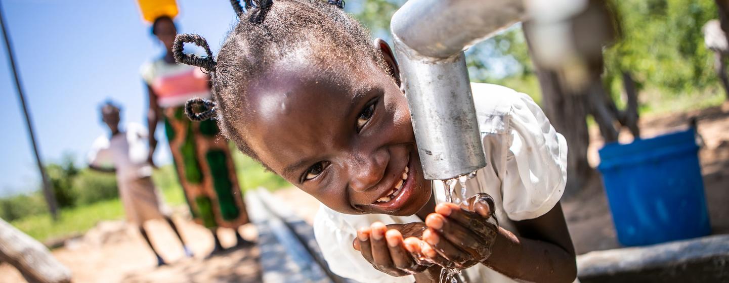 Une fillette au Zimbabwe boit de l'eau propre et salubre à un puits réhabilité avec le soutien de l'ONU.
