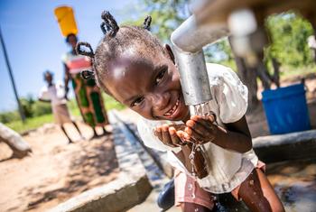 A young girl in Zimbabwe drinks clean and safe water from a well point rehabilitated with the support of the UN.