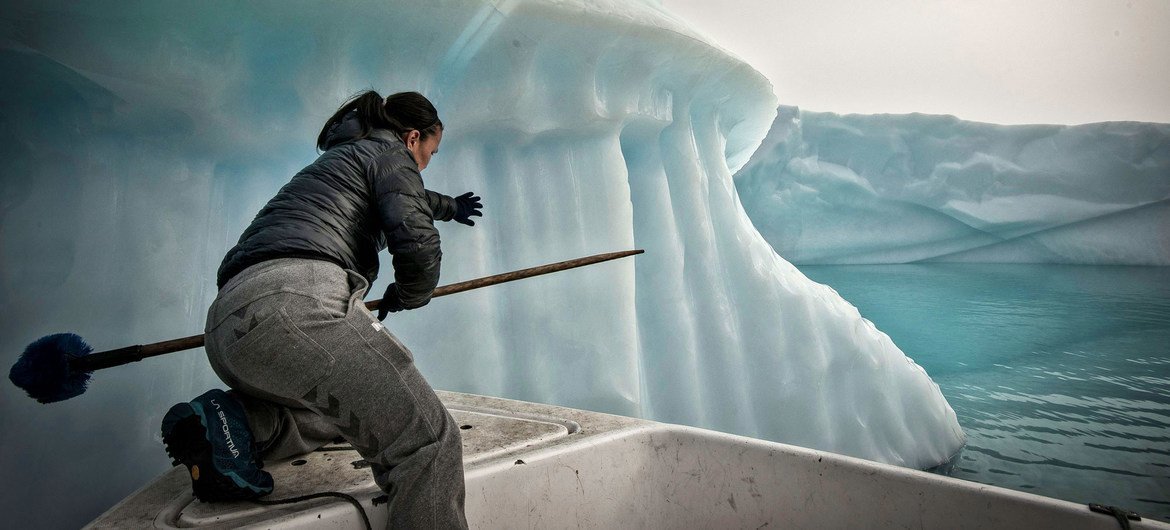 Um pescador tenta evitar que sua rede de pesca seja arrastada por um iceberg no mar da Groenlândia.