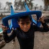 Un niño se protege de la lluvia con una silla de plástico azul en una zona inundada y llena de escombros en Bilwi, Nicaragua, tras la destrucción causada por el huracán Iota.