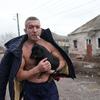 Un homme avec un chien devant une maison endommagée à Marioupol, dans le sud-est de l'Ukraine.