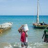 Pescadores carregam baldes no oceano perto de barcos no Haiti.