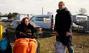 乌克兰妇女逃离不断升级的冲突，等待前往难民中心的汽车。