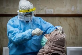 Un trabajador de salud hace la prueba del COVID-19 a un mujer en una clínica en Palestina.