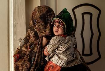 अफ़ग़ानिस्तान के कन्दाहार में, एक मेडिकल क्लीनिक में, एक महिला अपने बच्चे के साथ.