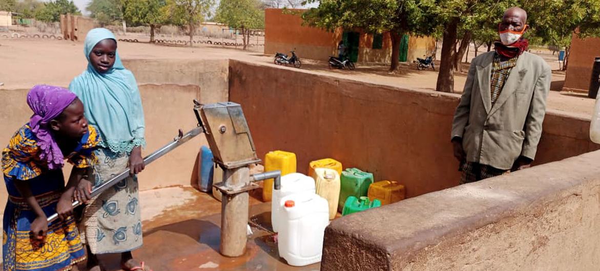 Retired civil servant Lambda and two of his granddaughters at a water pump in the commune of Tougouri, northern Burkina Faso.