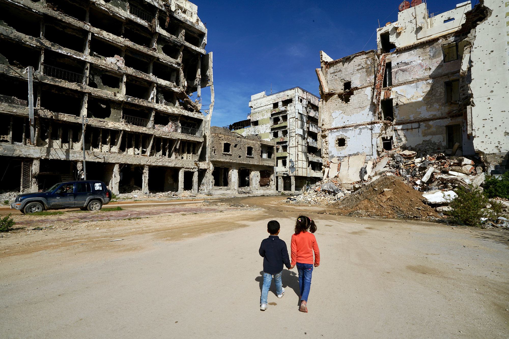 在利比亚的班加西，孩子们走过受损的建筑。