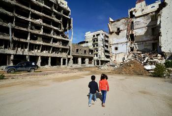 在利比亚的班加西，孩子们走过受损的建筑。