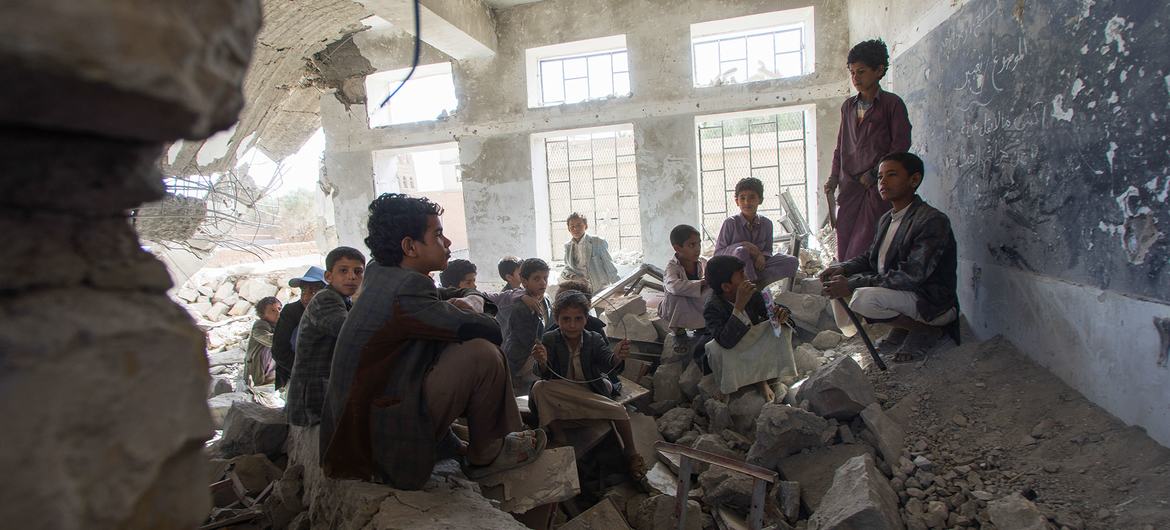 Children sit in a former classroom in a destroyed school in Saada City, Yemen. They now attend school in nearby UNICEF tents.