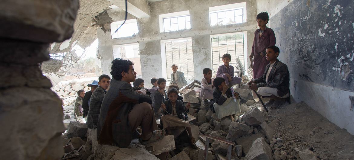 Crianças sentadas em uma antiga sala de aula em uma escola destruída na cidade de Saada, no Iêmen. Elas agora frequentam a escola em uma tenda do Unicef