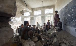 Children sit in a former classroom in a destroyed school in Saada City, Yemen. They now attend school in nearby UNICEF tents.