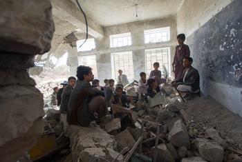Crianças sentadas em uma antiga sala de aula em uma escola destruída na cidade de Saada, no Iêmen. Elas agora frequentam a escola em uma tenda do Unicef