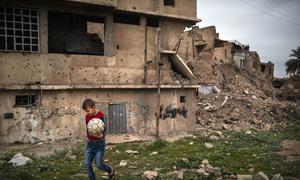 A boy carries a football ball in the Old City of Mosul in Iraq.
