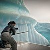 صياد يحاول منع شباك صيده من الانزلاق إلى أسفل من قبل جبل جليدي في بحر غرينلاند.