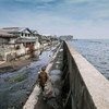 رجل يمشي على جدار بحري عملاق على طول ساحل جاكرتا بإندونيسيا