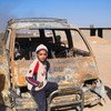 A young boy in Iraq stands next to a car that was torched by ISIL. (file)