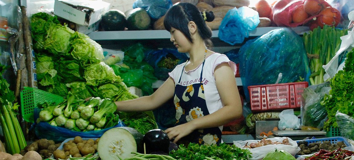 在北京，一名妇女在她的市场摊位上出售新鲜农产品。