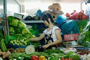 在北京，一名妇女在她的市场摊位上出售新鲜农产品。