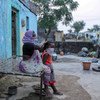 سيّدة تمشط شعر حفيدتها خارج منزلهما في الهند.