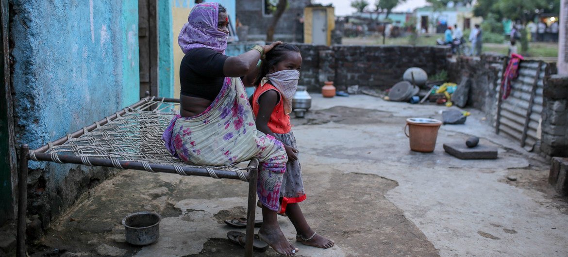 سيّدة تمشط شعر حفيدتها خارج منزلهما في الهند.