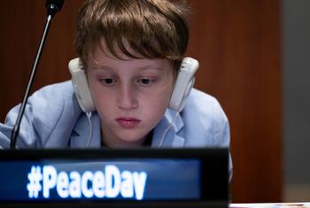 一位年轻的参与者在联合国总部收听”行动促和平：我们实现#全球目标#的决心”节目。
