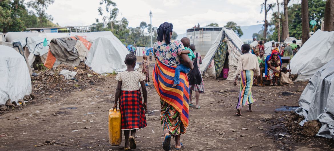 一位母亲和她的孩子走过刚果东部戈马的一处流离失所者营地。