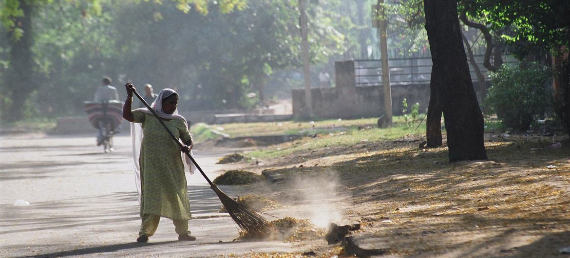 Une employée de maison balaie la rue dans un quartier de Delhi, en Inde.