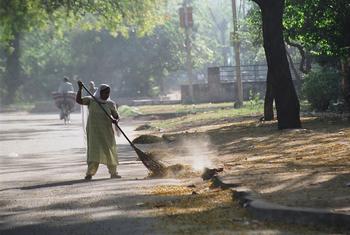 Una empleada doméstica barre la calle en un barrio de lujo de Delhi, India.