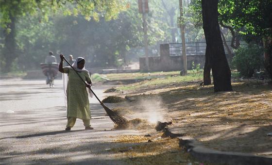 Una empleada doméstica barre la calle en un barrio de lujo de Delhi, India.