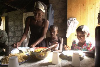 Una familia comiendo. La casa no tiene electricidad y los alimentos se cocinan fuera de la vivienda.