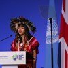 Txai Surui, uma mulher indígena, discursa em um pódio na Conferência das ONU sobre Mudanças Climáticas no Reino Unido em 2021.