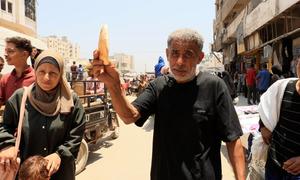 Gaza resident Ahmed Al-Bahri holds up a loaf of bread.