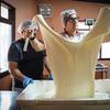 Guillermo desmenuza con su mano un queso mozzarella fresco para mostrar el proceso de producción artesanal que implica la elaboración de este tipo de queso.